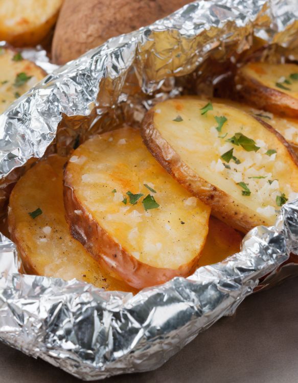 Grilled potato packets on a barbecue grill, seasoned to perfection