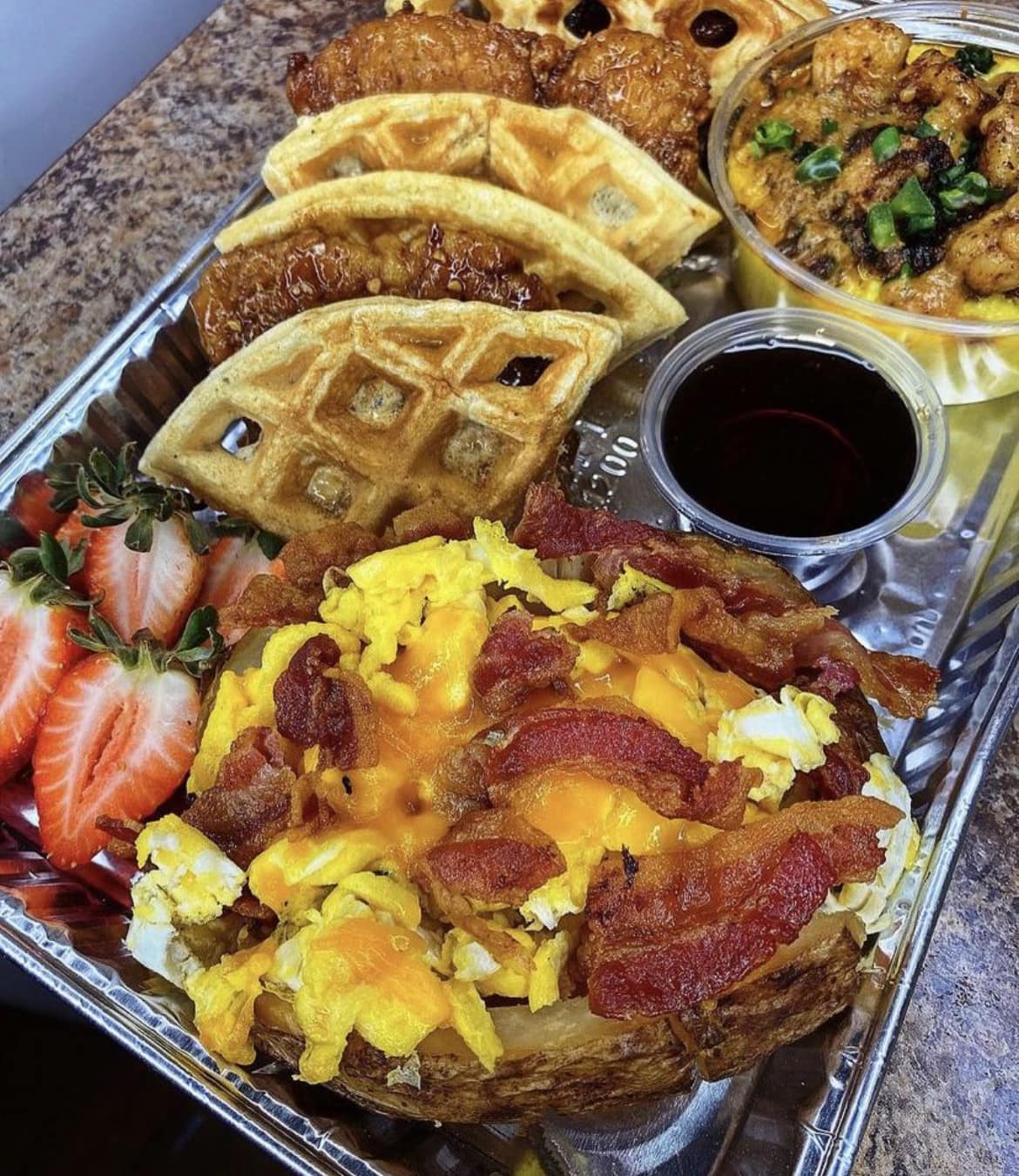 Three brunch dishes on a plate: Honey Chicken Sliders on mini buns, Shrimp & Grits in a bowl, and Loaded Breakfast Potatoes in a skillet.