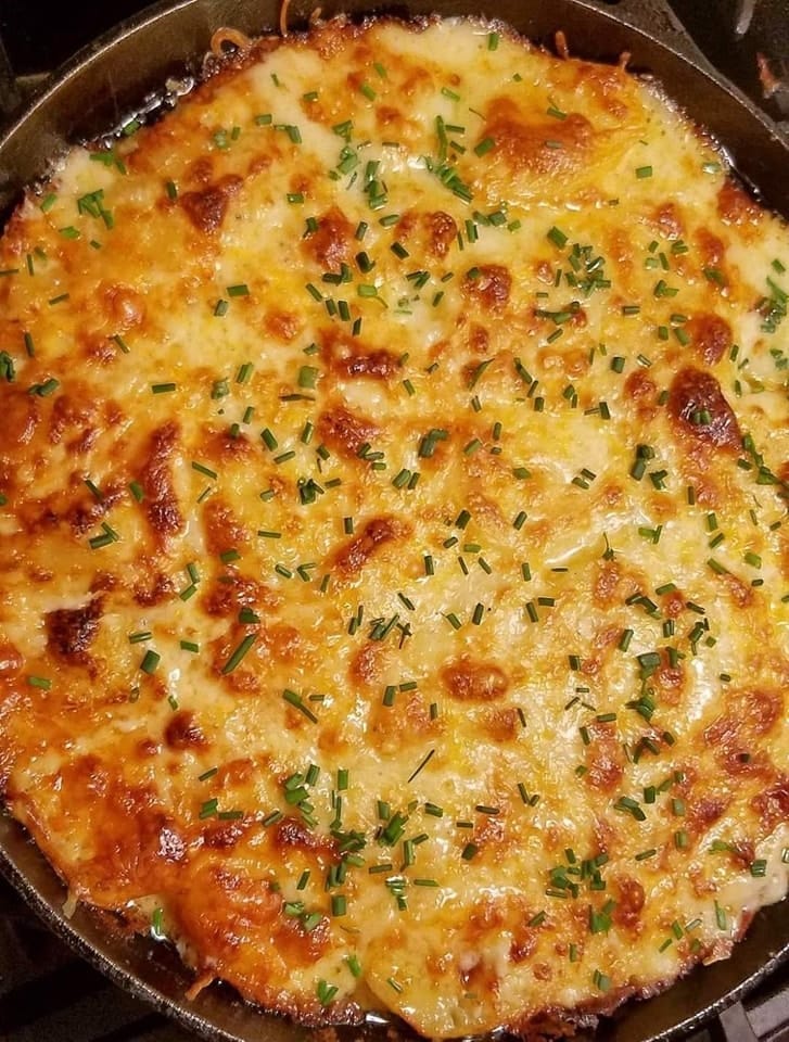 Potatoes DelMonico recipe showcasing layers of creamy potatoes and melted cheese in a baking dish.